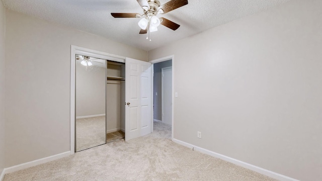 unfurnished bedroom featuring ceiling fan, light colored carpet, a textured ceiling, and a closet