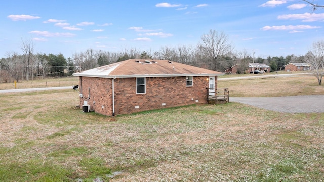 view of side of property with a yard and central AC