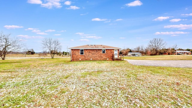 view of side of property with a lawn and a rural view