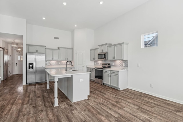 kitchen featuring gray cabinetry, sink, stainless steel appliances, and a high ceiling