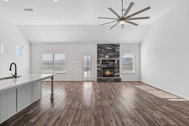 unfurnished living room featuring a stone fireplace, sink, dark hardwood / wood-style floors, and lofted ceiling