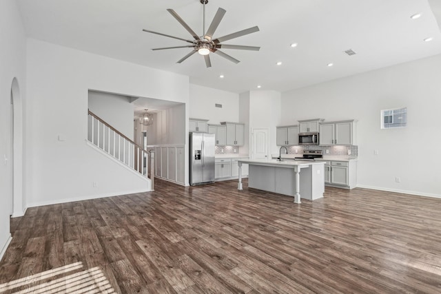 unfurnished living room featuring ceiling fan with notable chandelier, dark hardwood / wood-style floors, and sink