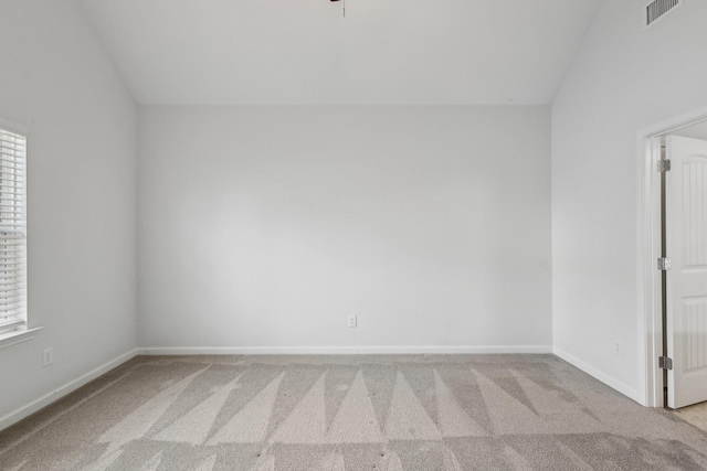 empty room featuring light colored carpet and lofted ceiling