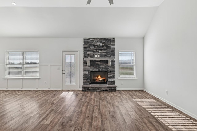 unfurnished living room with hardwood / wood-style floors, plenty of natural light, a stone fireplace, and vaulted ceiling