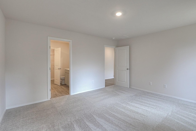 unfurnished bedroom featuring ensuite bathroom and light colored carpet