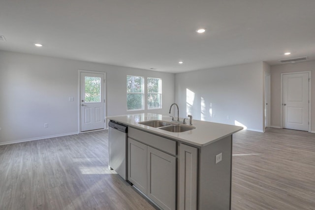 kitchen featuring light wood-type flooring, stainless steel dishwasher, sink, a center island with sink, and gray cabinets