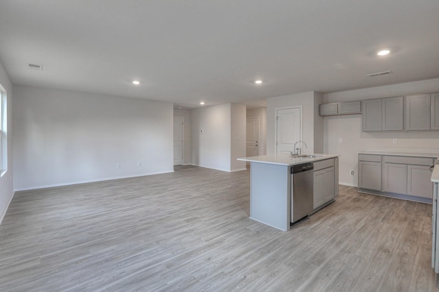 kitchen featuring dishwasher, sink, gray cabinets, a center island with sink, and light wood-type flooring