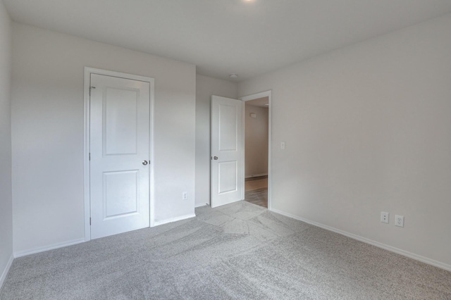 unfurnished bedroom with light colored carpet and a closet