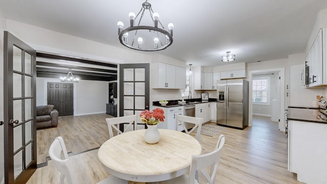 dining space featuring beamed ceiling, a notable chandelier, sink, and light hardwood / wood-style flooring