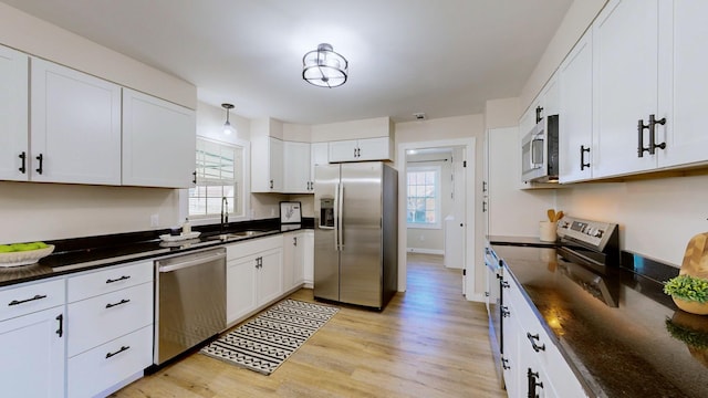 kitchen featuring sink, white cabinets, hanging light fixtures, and appliances with stainless steel finishes