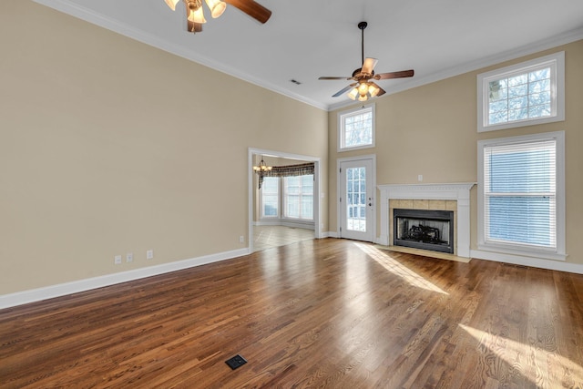 unfurnished living room featuring ceiling fan with notable chandelier, wood-type flooring, ornamental molding, and a tile fireplace