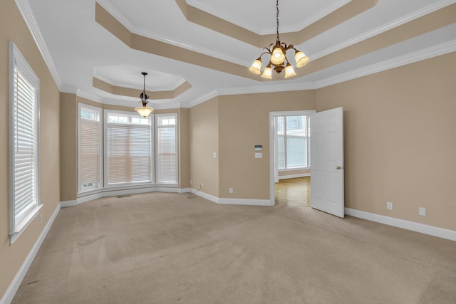 carpeted empty room featuring a notable chandelier, ornamental molding, and a tray ceiling