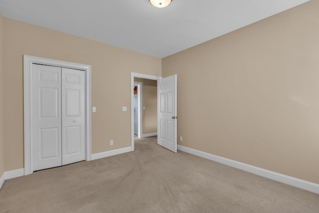 unfurnished bedroom featuring light colored carpet and a closet