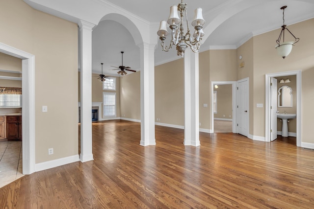 unfurnished living room featuring hardwood / wood-style floors, ceiling fan with notable chandelier, crown molding, and sink