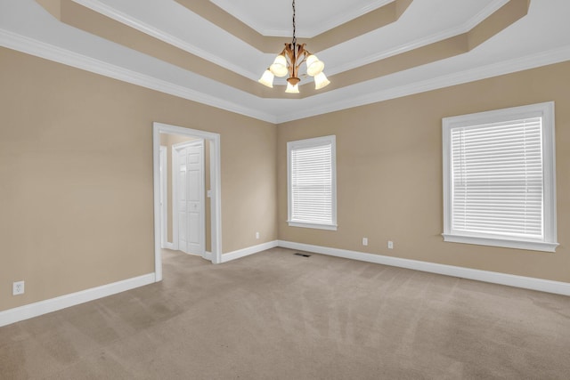 carpeted empty room featuring a chandelier, a raised ceiling, and crown molding