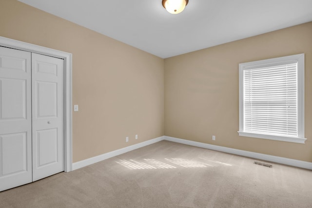 unfurnished bedroom featuring light carpet and a closet