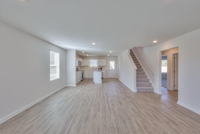 unfurnished living room featuring light hardwood / wood-style floors, a wealth of natural light, and sink