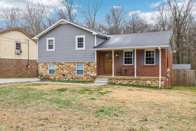 tri-level home featuring a porch, cooling unit, and a front lawn