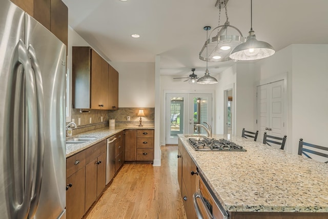 kitchen with ceiling fan, sink, decorative light fixtures, a center island with sink, and appliances with stainless steel finishes