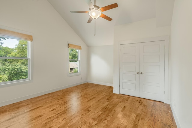 unfurnished bedroom featuring ceiling fan, a closet, light wood-type flooring, and vaulted ceiling