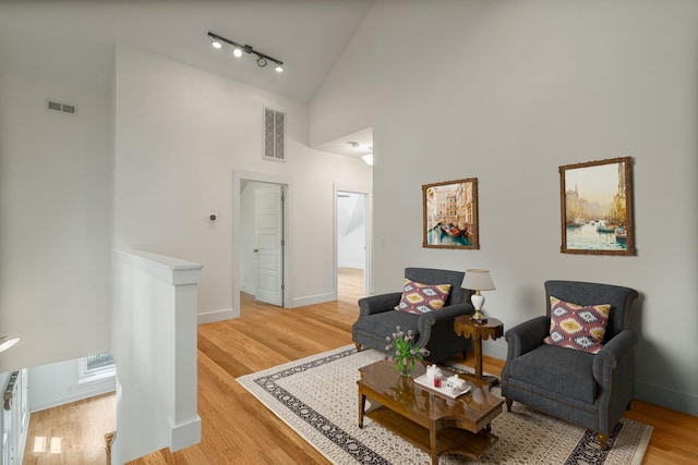 living area featuring rail lighting, high vaulted ceiling, and light wood-type flooring