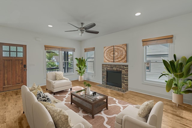 living room featuring a fireplace, light hardwood / wood-style floors, and ceiling fan