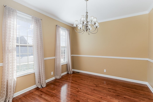 empty room featuring crown molding, dark hardwood / wood-style floors, and a notable chandelier