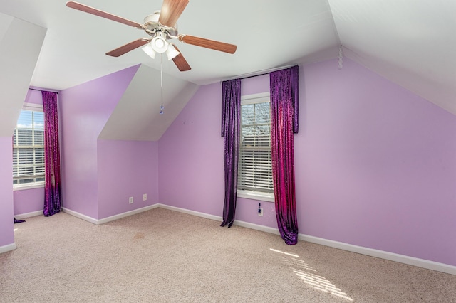 additional living space with lofted ceiling, plenty of natural light, light colored carpet, and ceiling fan