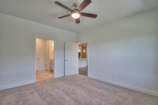 unfurnished bedroom featuring ceiling fan, light colored carpet, and ensuite bathroom