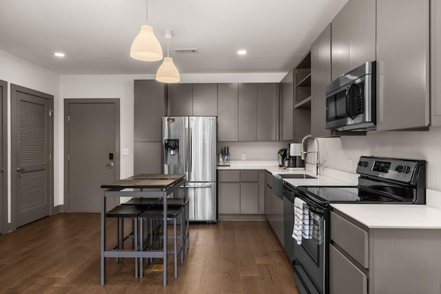 kitchen with appliances with stainless steel finishes, gray cabinetry, sink, decorative light fixtures, and dark hardwood / wood-style floors