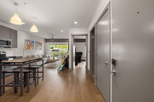 kitchen with ceiling fan, light wood-type flooring, and hanging light fixtures