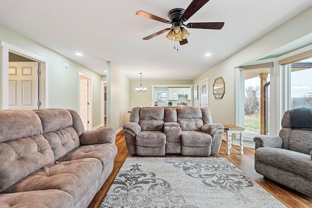 living room with wood-type flooring and ceiling fan with notable chandelier