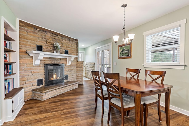 dining room featuring dark hardwood / wood-style flooring, a fireplace, a chandelier, and french doors