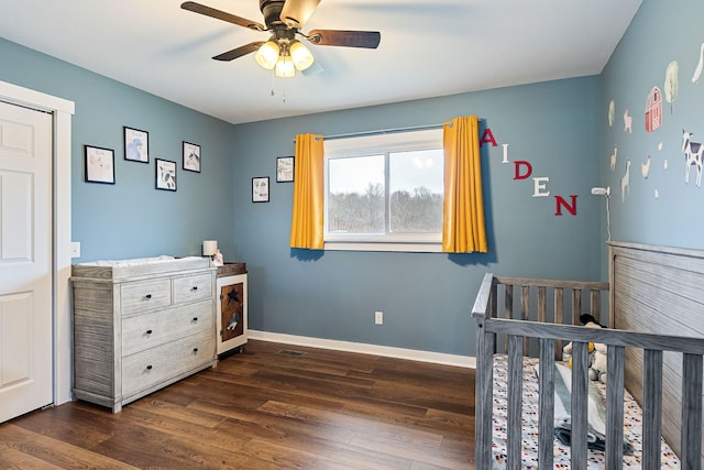 bedroom featuring ceiling fan, dark hardwood / wood-style floors, and a nursery area