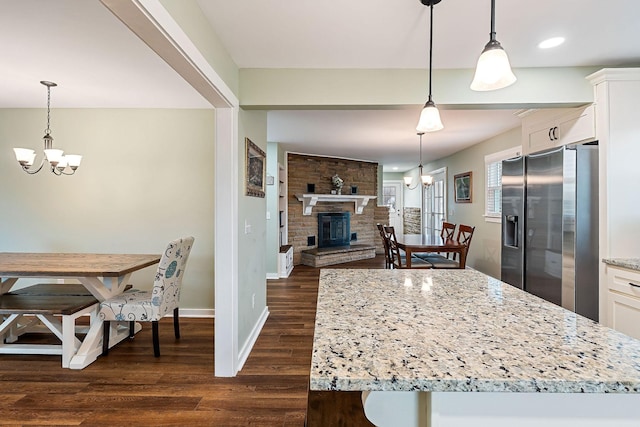 kitchen with stainless steel fridge, white cabinets, hanging light fixtures, and a notable chandelier