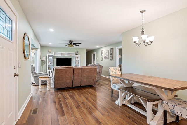 living room with ceiling fan with notable chandelier and dark wood-type flooring