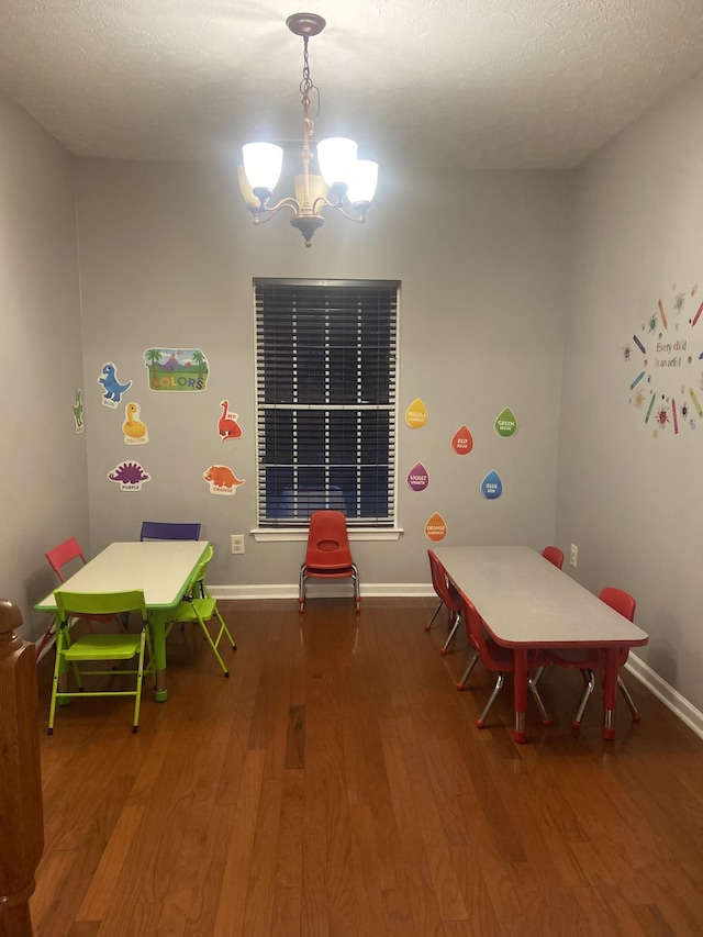 game room featuring an inviting chandelier, wood-type flooring, and a textured ceiling