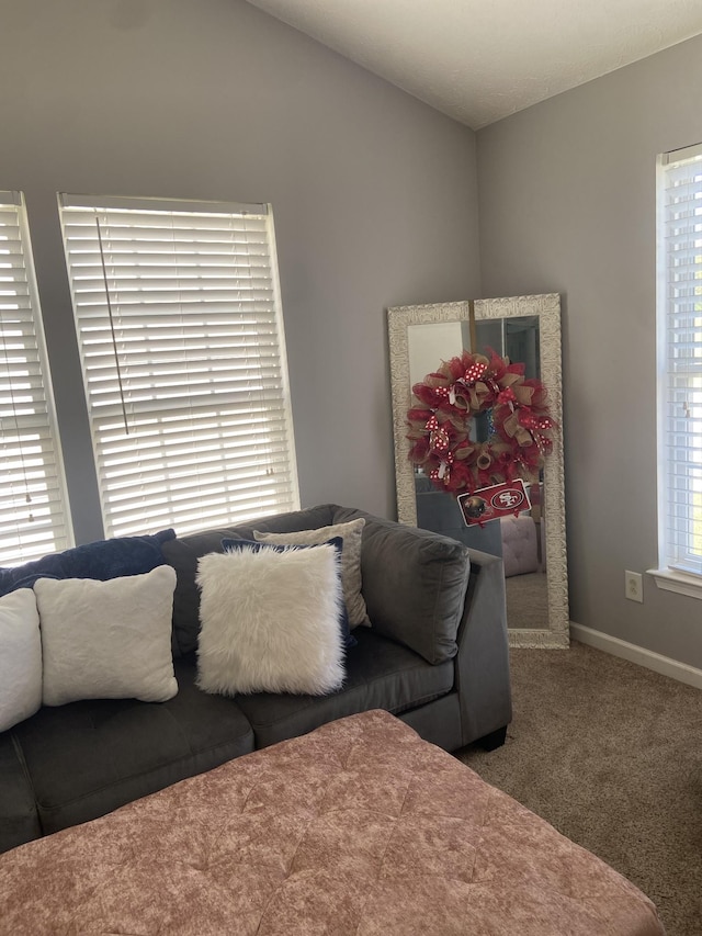 living room featuring a wealth of natural light, vaulted ceiling, and carpet