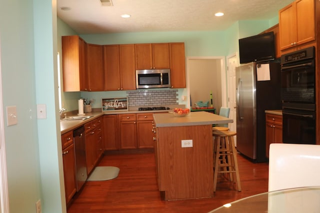 kitchen featuring dark hardwood / wood-style floors, a breakfast bar area, appliances with stainless steel finishes, and a kitchen island