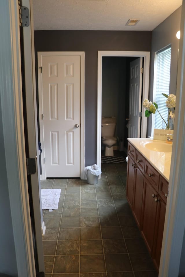 bathroom featuring vanity, a textured ceiling, and toilet