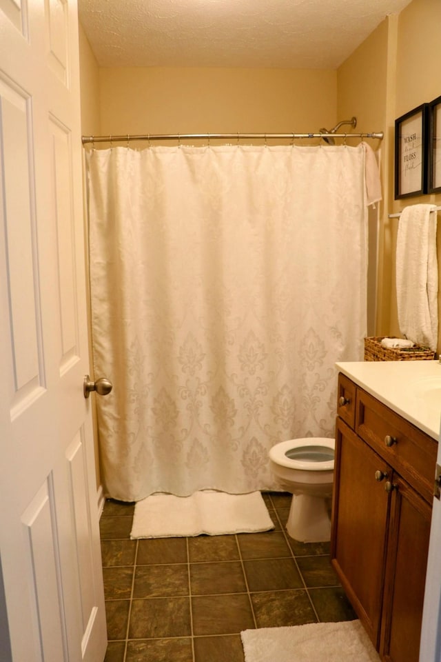 bathroom with vanity, tile patterned floors, toilet, and a textured ceiling