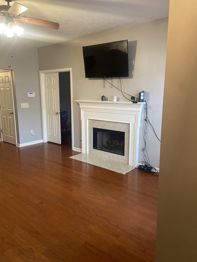 unfurnished living room with a high end fireplace, dark hardwood / wood-style floors, and ceiling fan