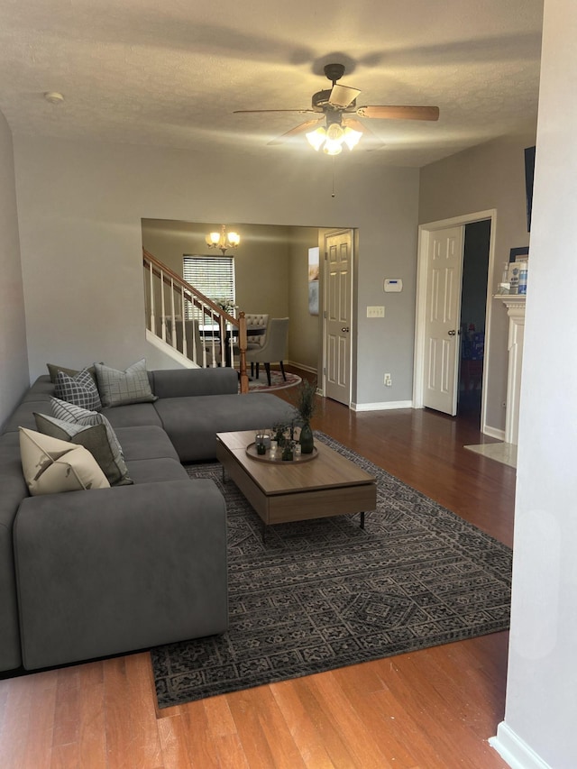 living room with hardwood / wood-style flooring, ceiling fan with notable chandelier, and a textured ceiling