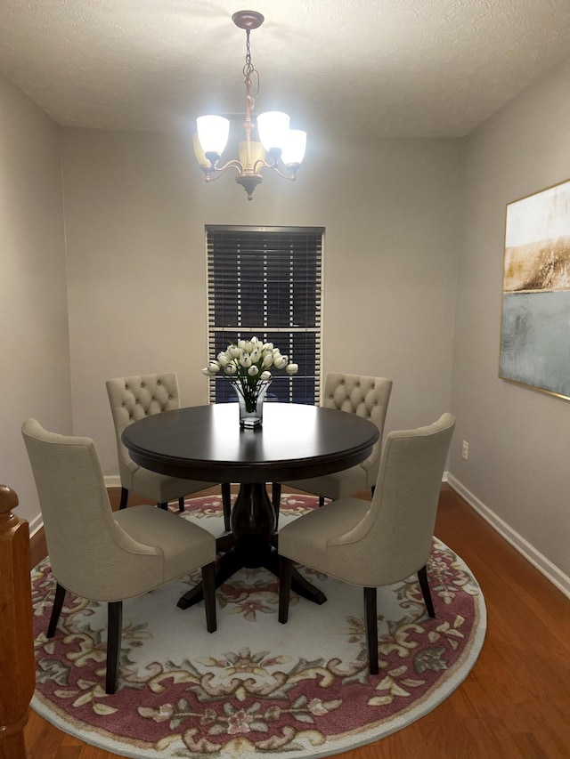 dining space with an inviting chandelier, hardwood / wood-style floors, and a textured ceiling