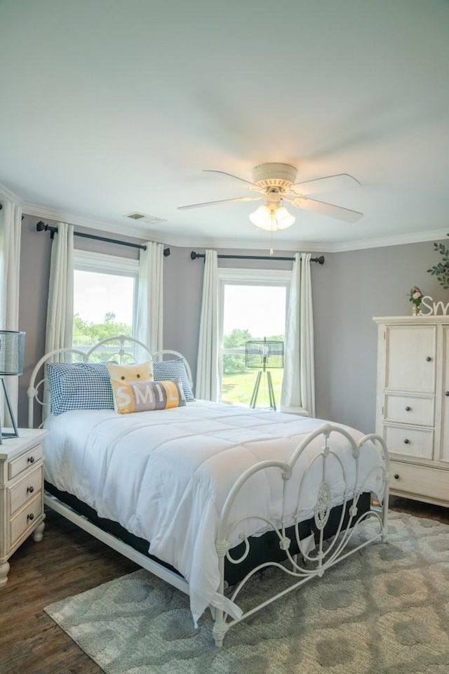 bedroom with dark hardwood / wood-style flooring, ceiling fan, and ornamental molding