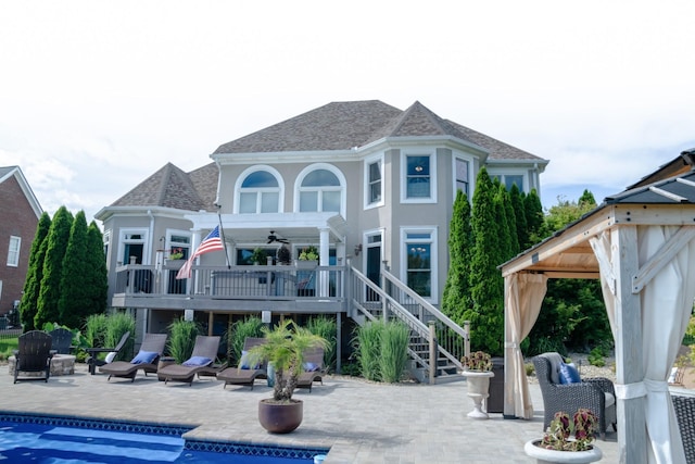 back of property featuring a gazebo, ceiling fan, a patio area, and a swimming pool side deck