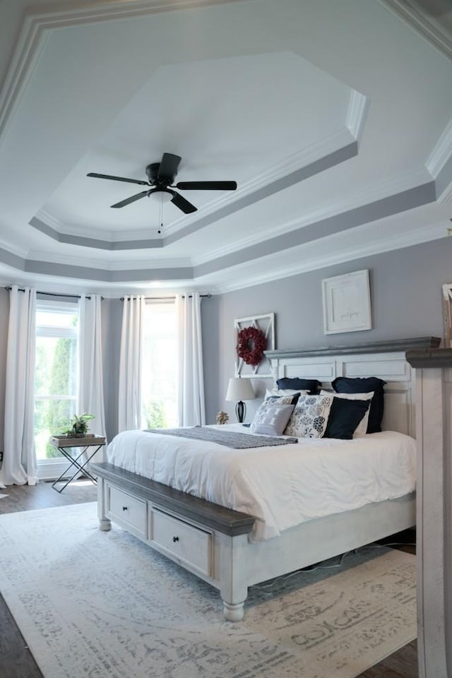 bedroom with hardwood / wood-style floors, ceiling fan, a raised ceiling, and ornamental molding