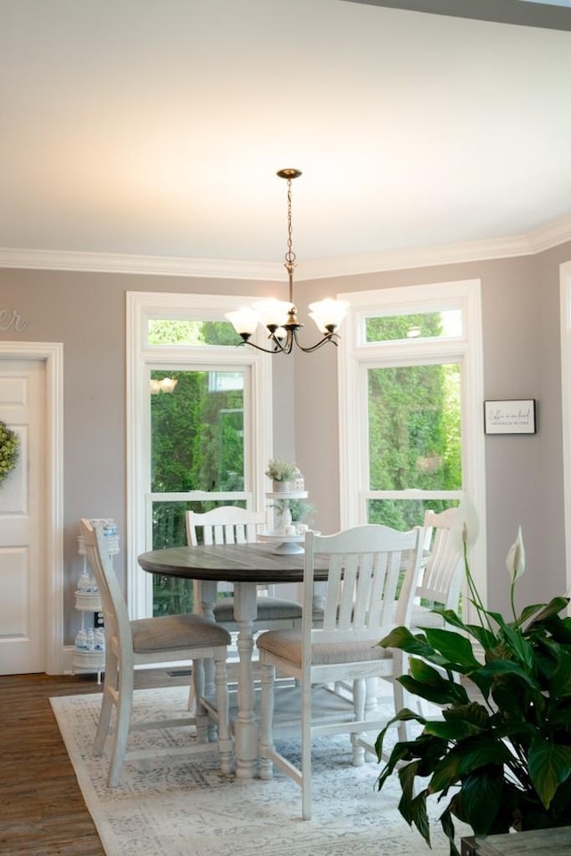 dining space featuring ornamental molding, dark wood-type flooring, and a notable chandelier