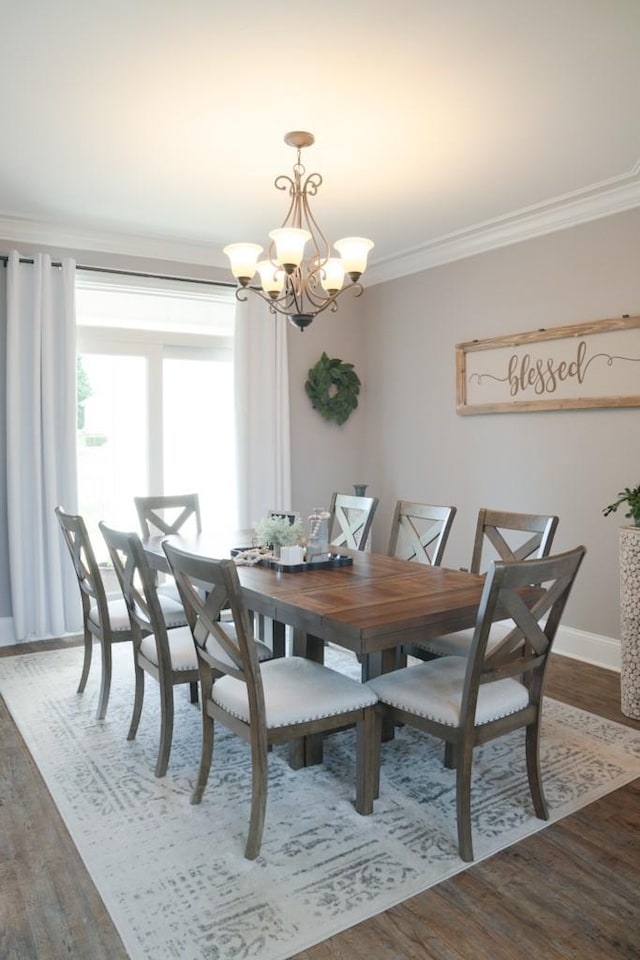 dining space featuring dark hardwood / wood-style flooring, an inviting chandelier, and crown molding