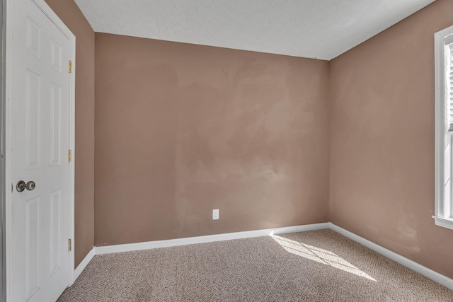 carpeted spare room featuring baseboards and a textured ceiling